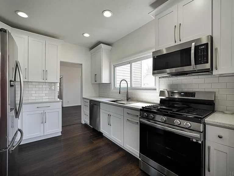 Remodeled kitchen with white shaker cabinets, subway tile backsplash, and stainless appliances