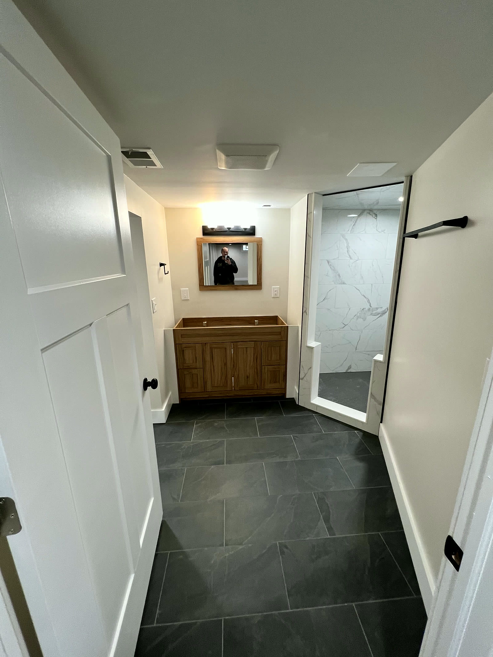 Finished basement bathroom with wood vanity and tiled shower