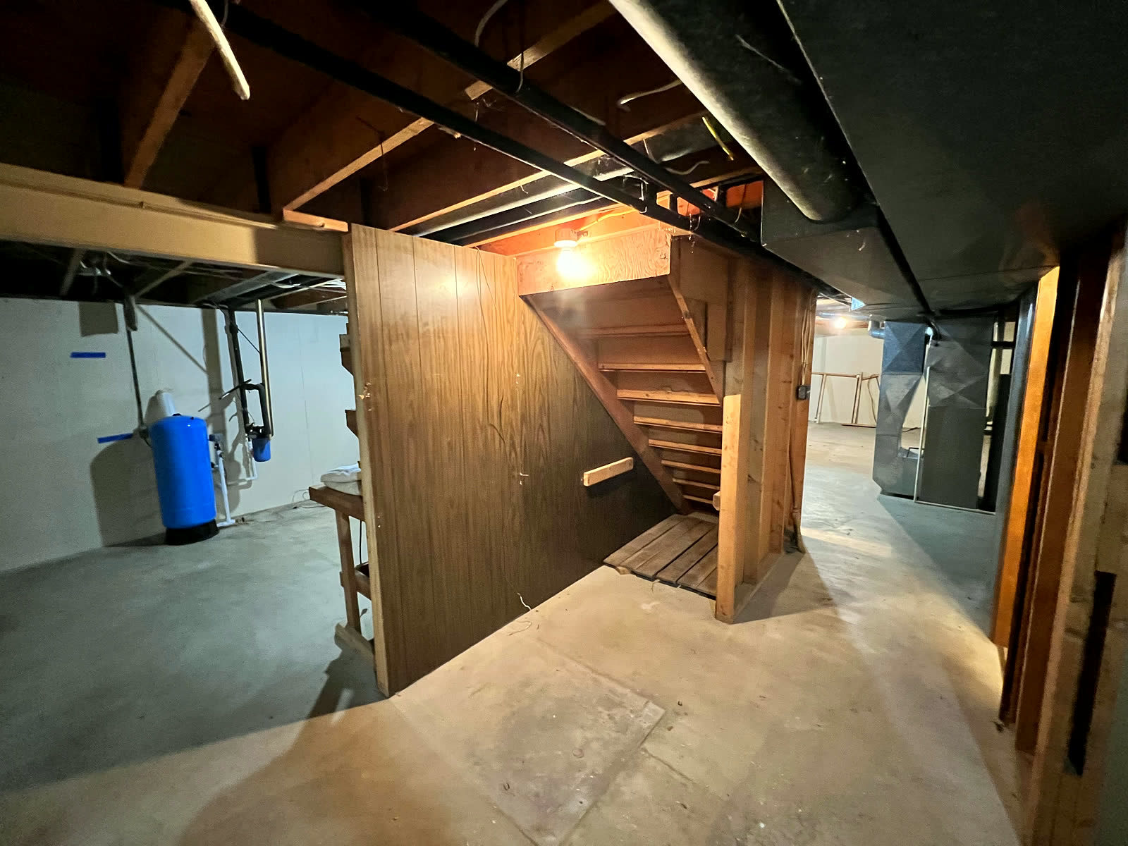 Basement before — bare concrete floor and exposed joists