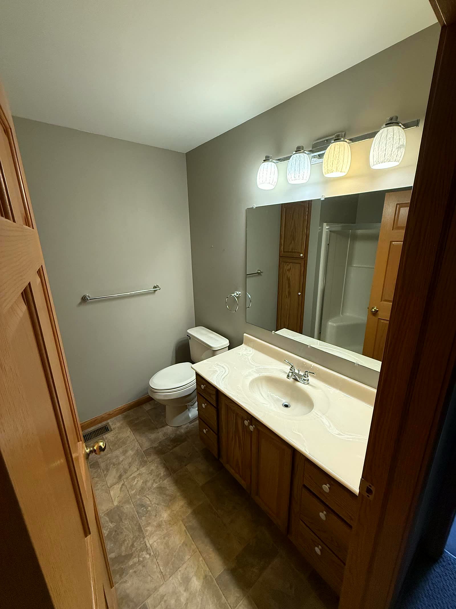 Bathroom before remodel — dated oak vanity and vinyl floor