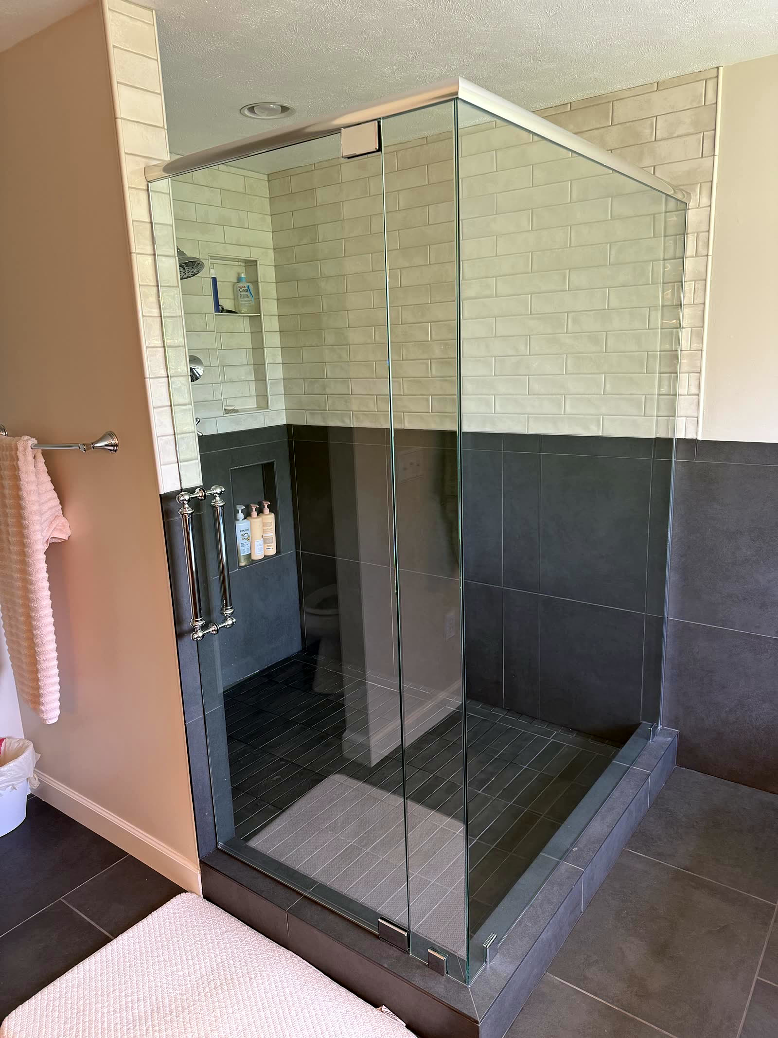 Renovated master bathroom with frameless glass two-tone tiled shower
