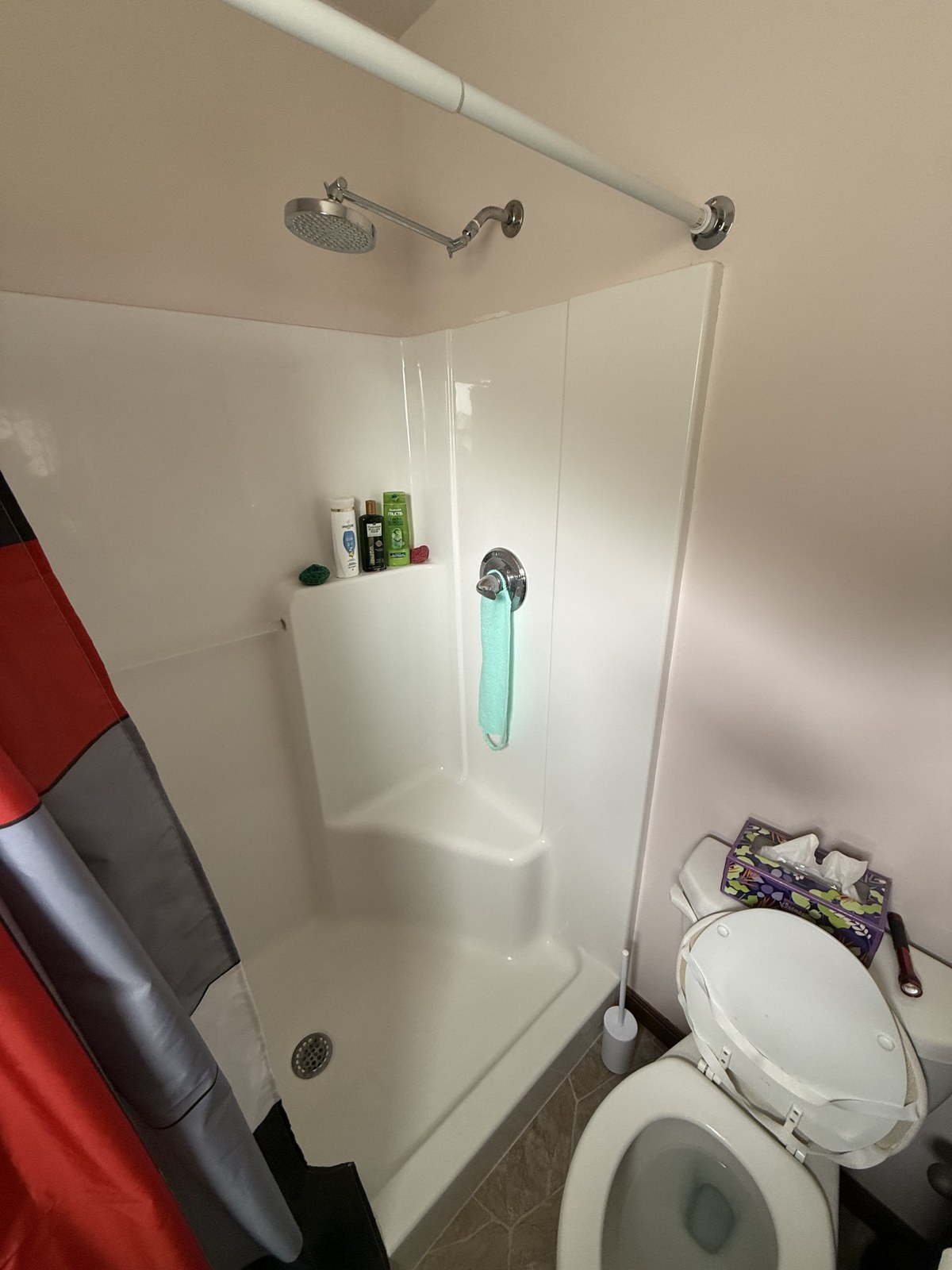 Bathroom before remodel — dated shower and worn flooring