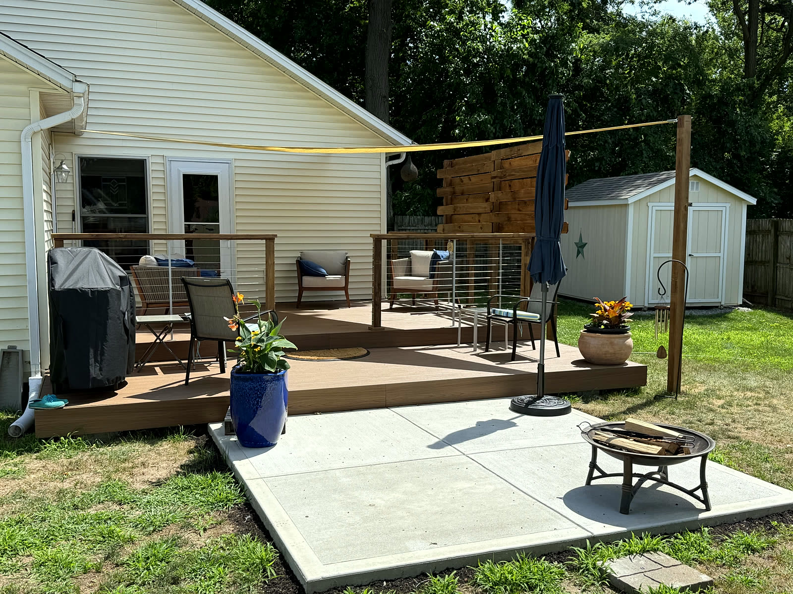 Custom composite deck with horizontal-slat railing and poured concrete patio