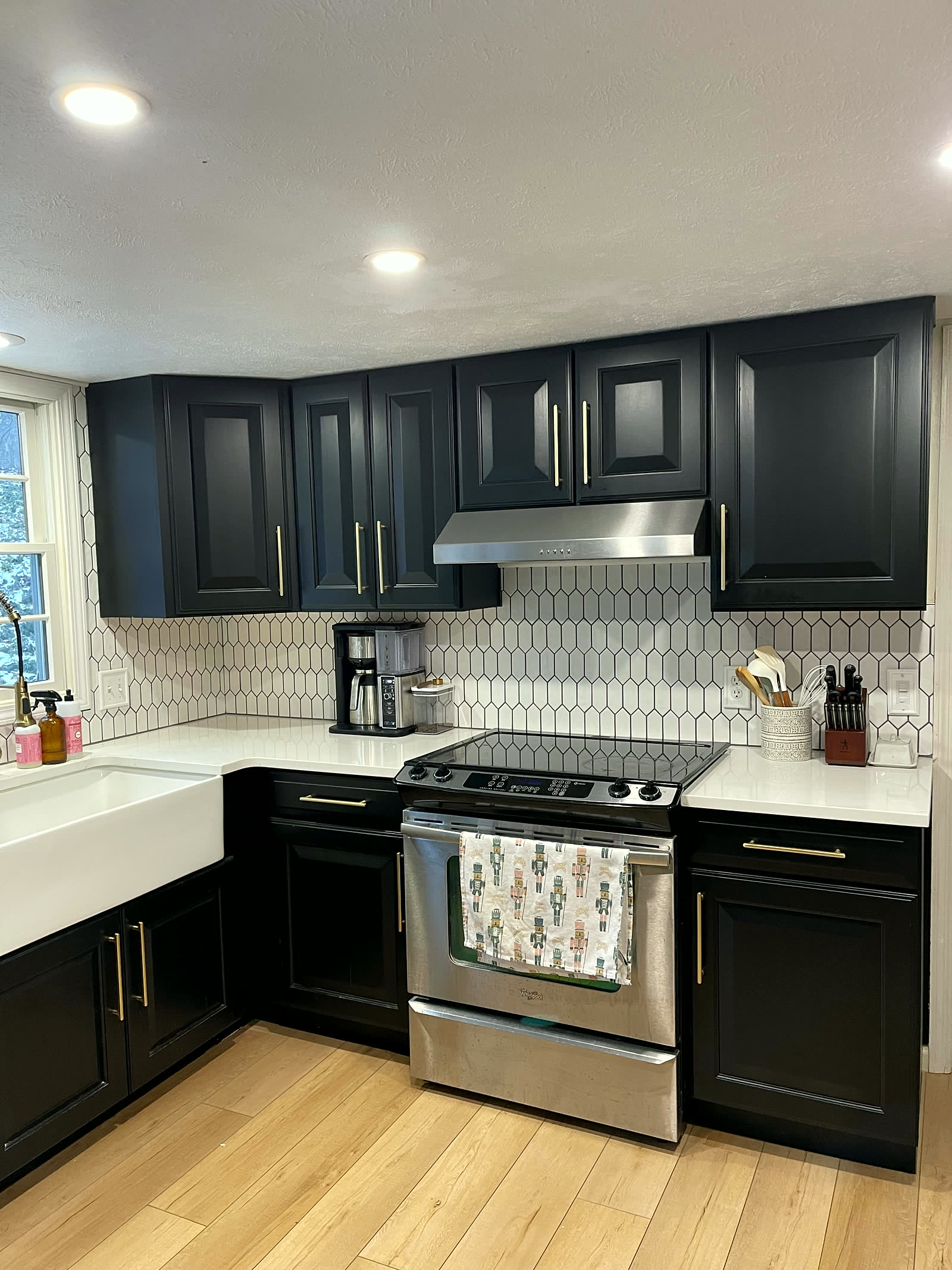 Remodeled kitchen with navy cabinets, white quartz counters, gold hardware, and picket tile backsplash