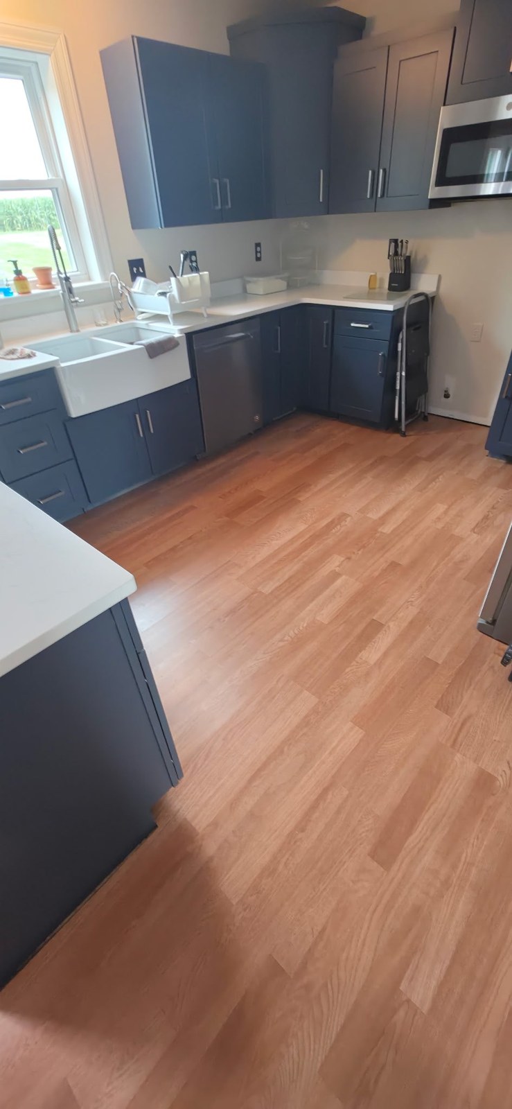 Kitchen after new flooring — warm hardwood floor with navy cabinets