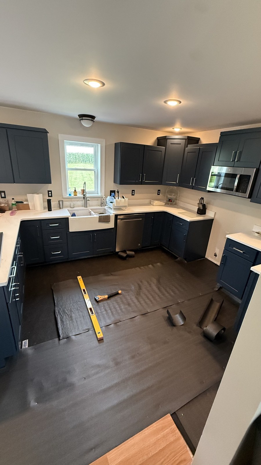 Kitchen before new flooring — worn dark floor with navy cabinets