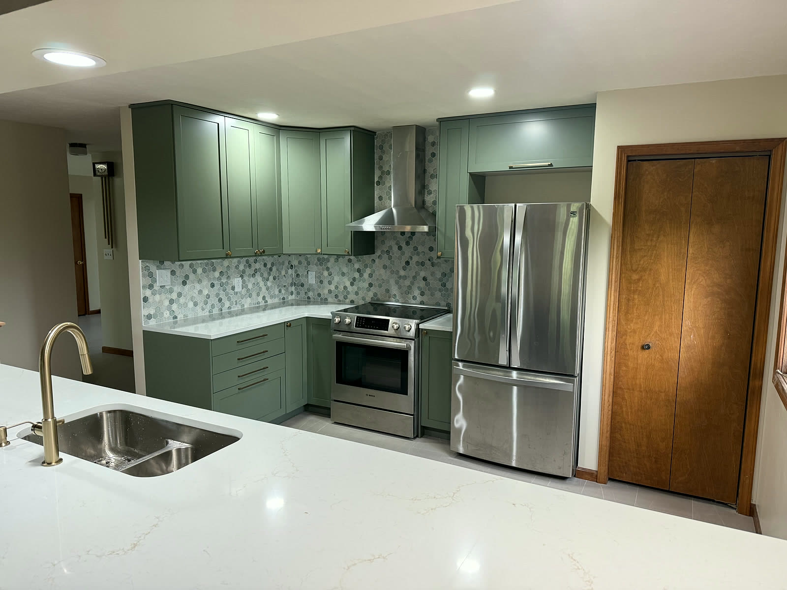 Finished sage-green kitchen with quartz waterfall island and gold fixtures
